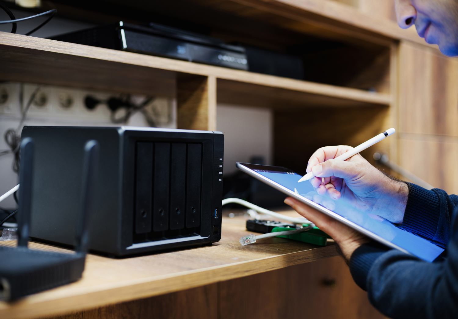 SynoRepair - Mann mit Tablet an Schreibtisch prüft und repariert Synology NAS
