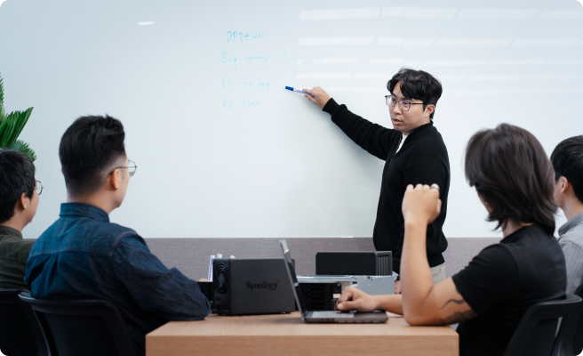 Picture of the team discussing in front of a white board.
