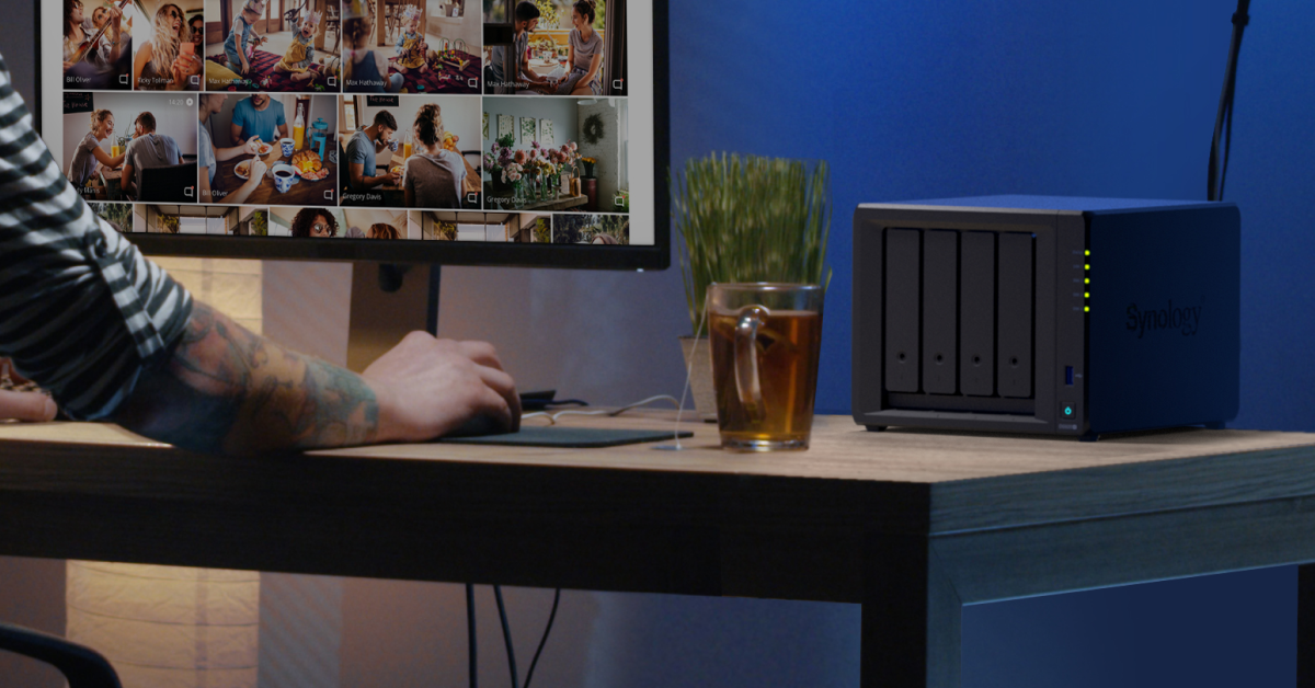 Photo library on a computer screen beside a Synology DiskStation on a desk